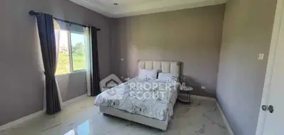 Spacious bedroom with elegant decor and large window offering natural light