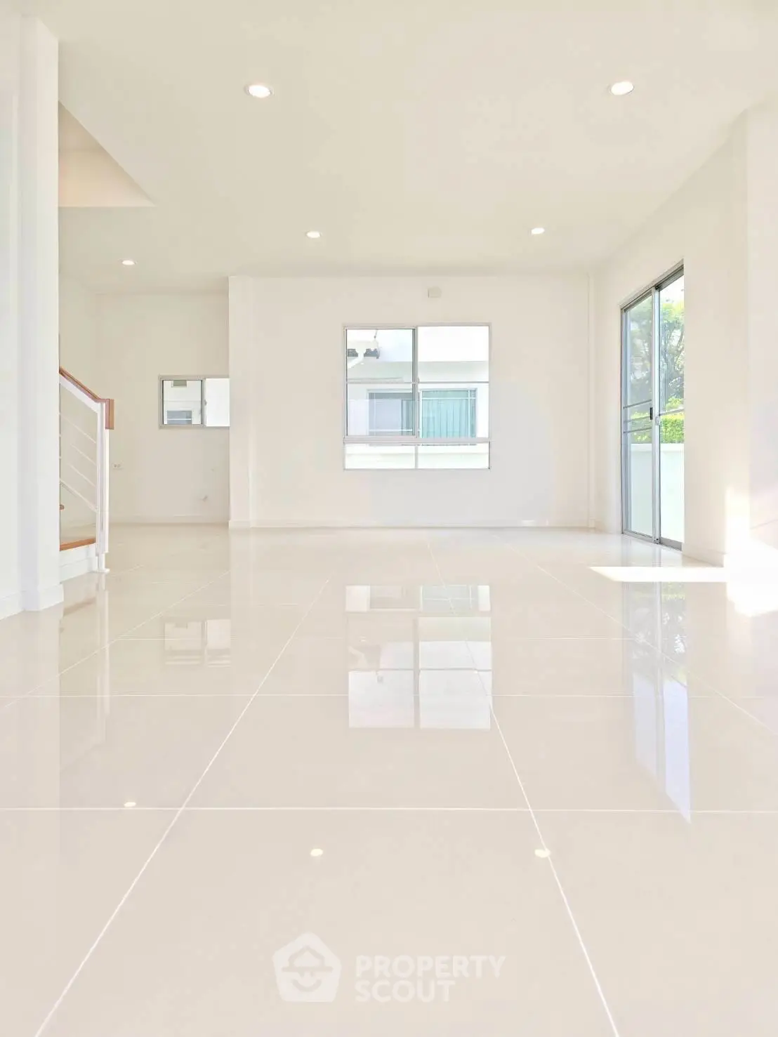 Spacious modern living room with large windows and glossy tile flooring, perfect for natural light lovers.