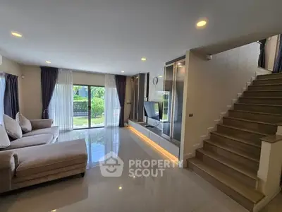 Spacious modern living room with large windows and elegant staircase