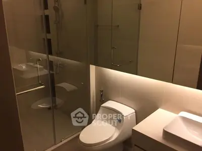 Modern bathroom with glass shower and sleek fixtures in contemporary apartment.