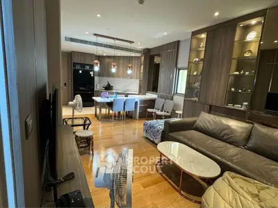 Modern living room with open kitchen, stylish furniture, and wooden flooring.