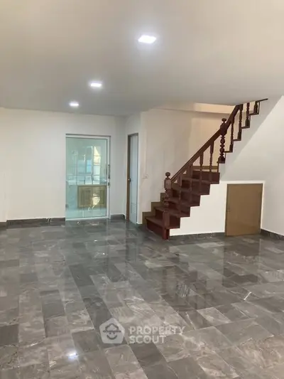 Spacious modern interior with marble flooring and wooden staircase, ideal for stylish living.