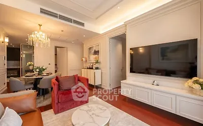 Luxurious living room with elegant decor and modern furnishings, featuring a large flat-screen TV and stylish chandelier.