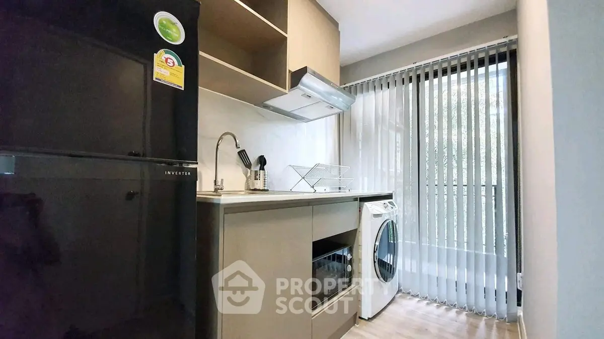 Modern kitchen with washing machine and oven, sleek cabinetry, and natural light.