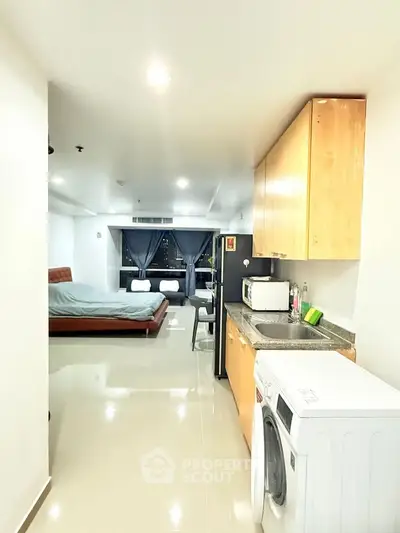 Modern studio apartment with open kitchen and city view, featuring sleek appliances and cozy living space.