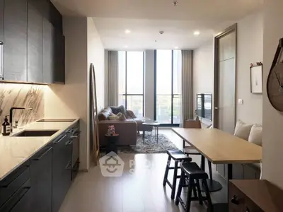 Modern open-plan kitchen and living room with sleek design and large windows.
