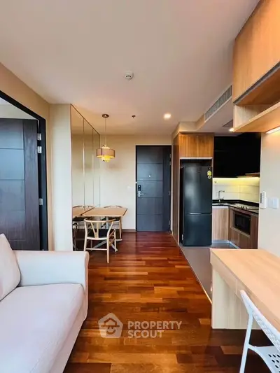 Modern open-plan living room with wooden flooring and sleek kitchen design