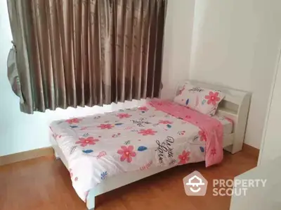 Cozy bedroom with floral bedding and wooden flooring, perfect for a peaceful retreat.