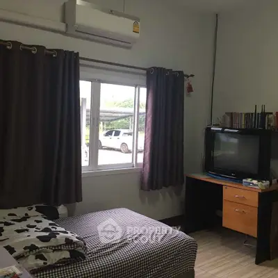 Cozy bedroom with window view, air conditioning, and TV setup, perfect for relaxation.