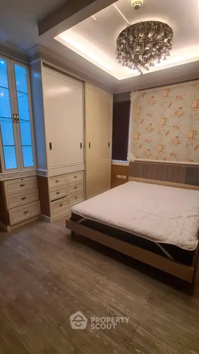 Elegant bedroom with modern chandelier and built-in storage