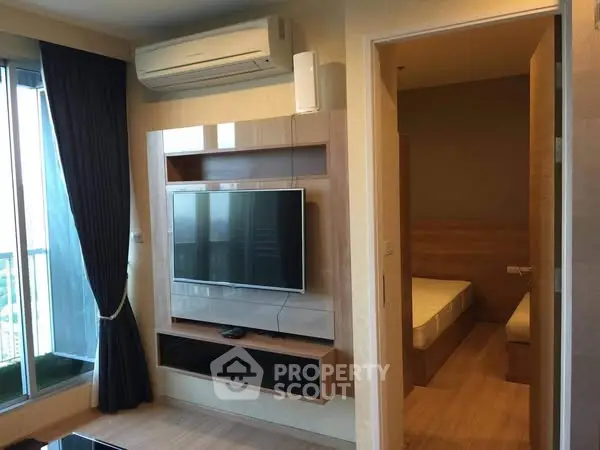 Modern living room with wall-mounted TV and adjacent bedroom in a cozy apartment.