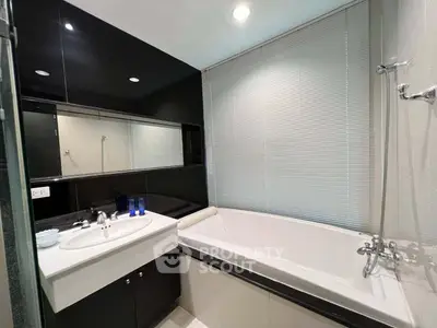 Modern bathroom with sleek black accents and a spacious bathtub.