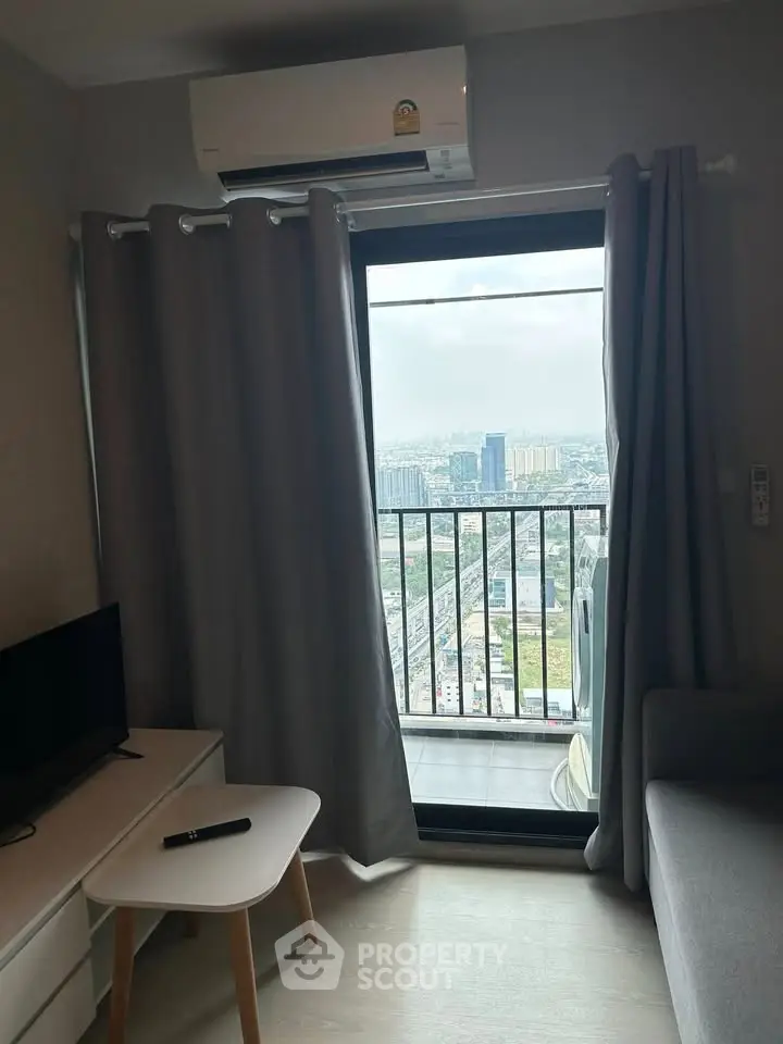 Modern living room with balcony offering stunning city view, featuring sleek furniture and air conditioning.