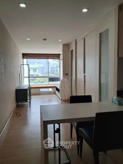 Modern living room with sleek furniture and large window offering natural light and neighborhood view.