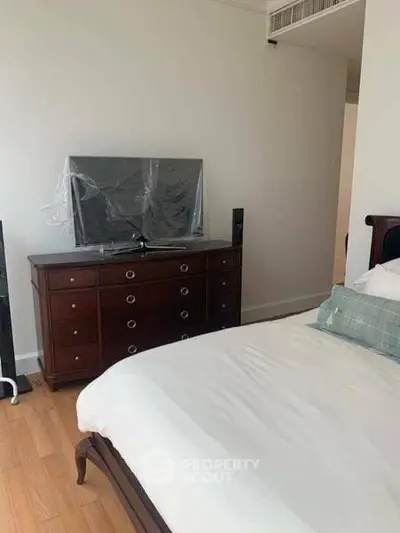 Spacious bedroom with elegant wooden furniture and modern TV setup.