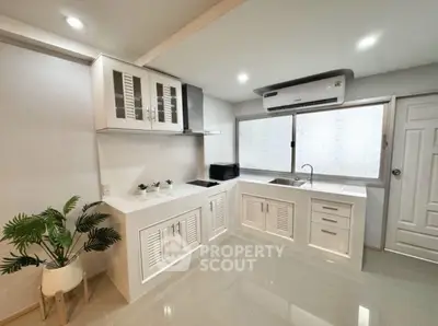 Modern kitchen with sleek white cabinetry and air conditioning unit