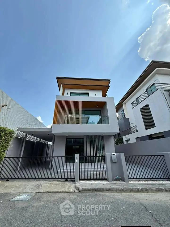Modern three-story house with sleek design and spacious balcony, perfect for contemporary living.