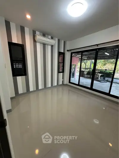 Spacious room with striped accent wall and large sliding glass doors leading to a balcony.