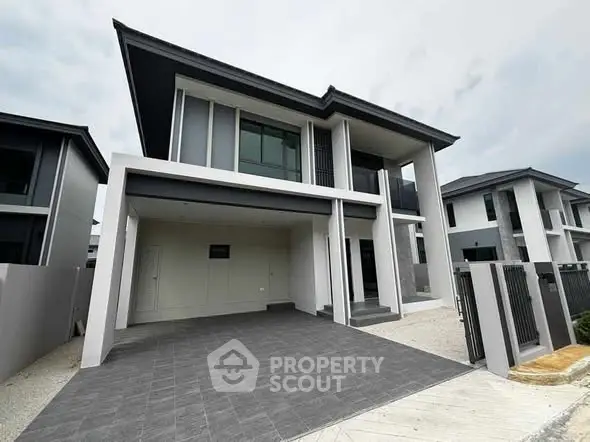 Modern two-story house with sleek design and spacious driveway in a suburban neighborhood.