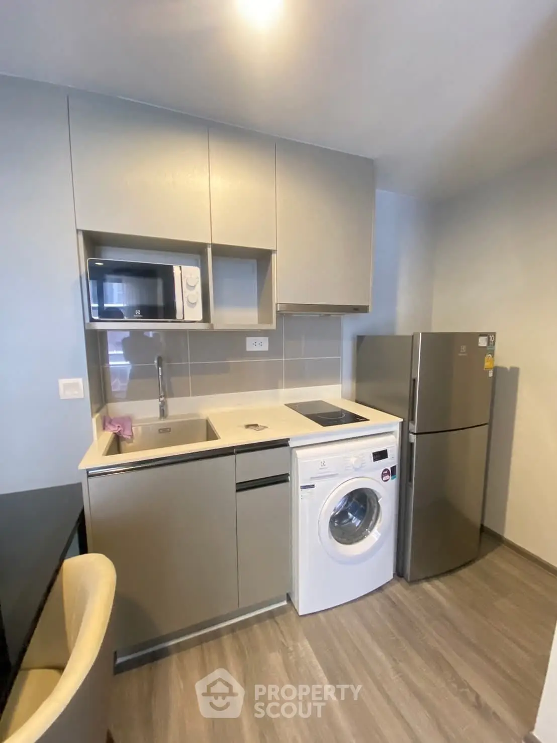 Modern compact kitchen with washing machine and fridge in a cozy apartment.