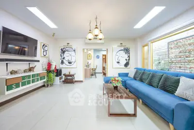 Spacious living room with modern decor and blue sofa, ideal for family gatherings.