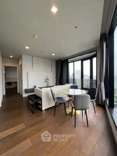 Modern living room with city view, elegant furniture, and wooden flooring.