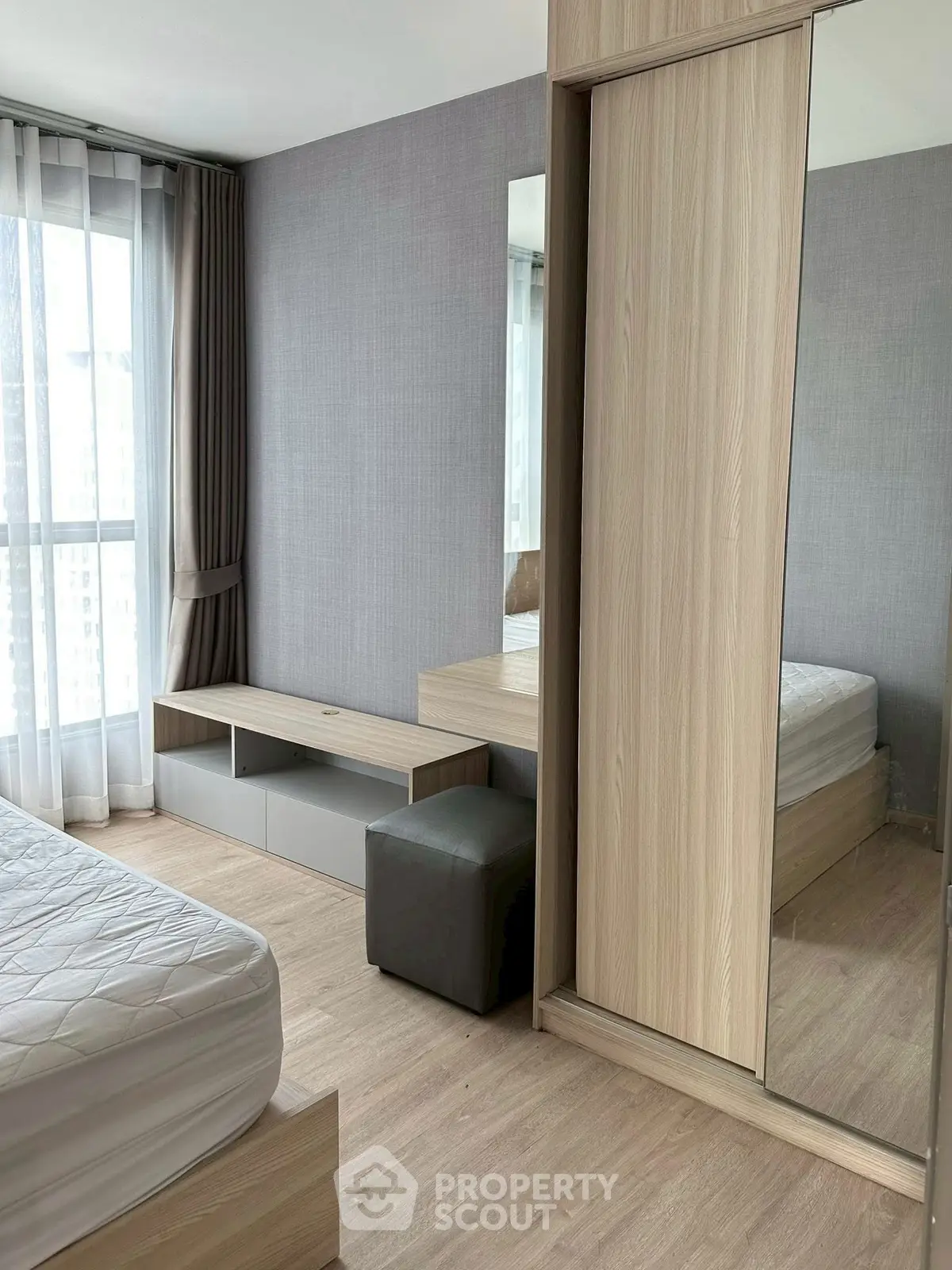 Modern bedroom with large window and mirrored wardrobe in stylish apartment