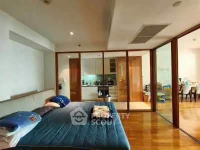 Spacious bedroom with glass partition leading to a modern kitchen and dining area.