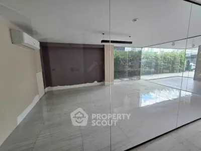 Spacious empty room with large glass windows and modern air conditioning unit.