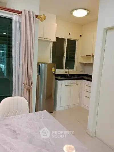 Modern kitchen with sleek design, stainless steel fridge, and elegant dining area.