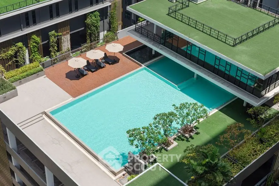 Luxurious rooftop pool with modern design and lush greenery in a high-rise building.