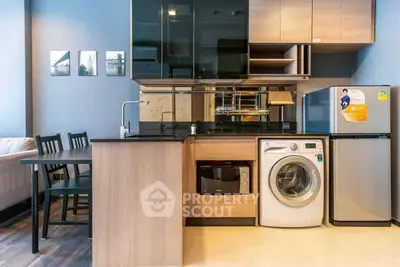 Modern kitchen with washing machine and fridge in compact open layout.