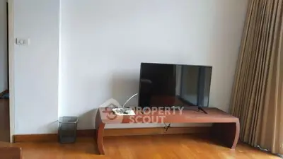 Minimalist living room with wooden floor and TV on stylish table.