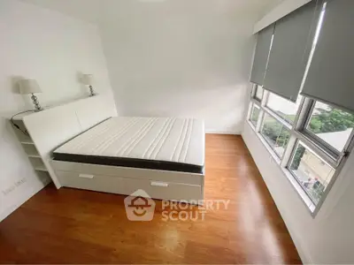 Spacious bedroom with large windows and modern furnishings in a bright apartment.