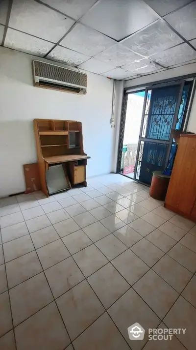 Spacious room with tiled flooring, large windows allowing natural light, and an air conditioning unit, ready for customization.