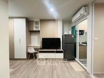 Modern living room with sleek design, featuring a TV, air conditioning, and adjacent kitchen area.