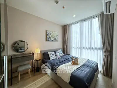 Cozy bedroom with modern decor, large window, and stylish furniture in a well-lit apartment.