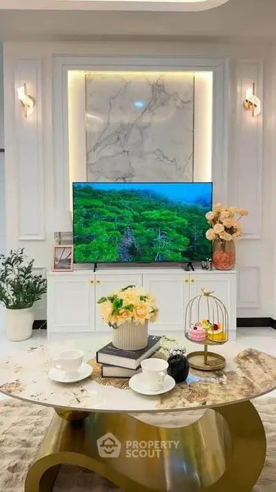 Luxurious living room with elegant decor, marble accents, and modern TV setup.