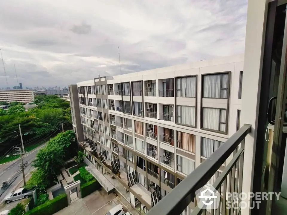 Modern apartment building with spacious balconies and lush green surroundings.