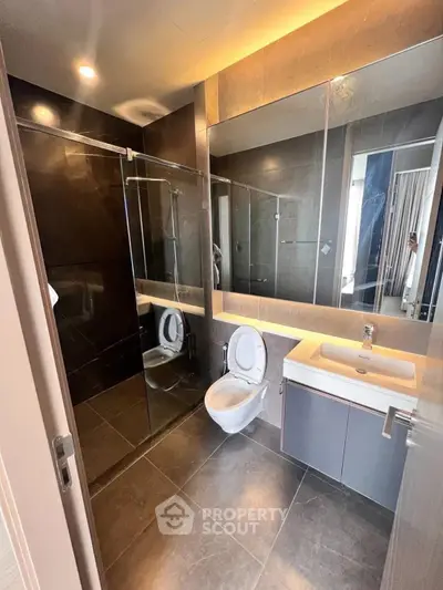 Modern bathroom with sleek design, glass shower, and wall-mounted toilet in luxury apartment.