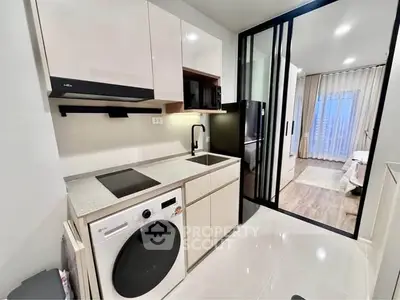 Modern kitchen with sleek appliances and open layout leading to a bright living area.