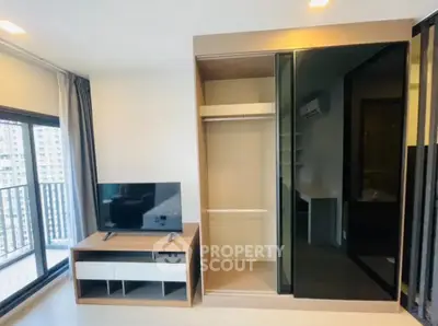 Modern living room with balcony view and sleek storage solutions in urban apartment.