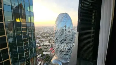Stunning cityscape view from a high-rise building balcony overlooking a unique architectural landmark.