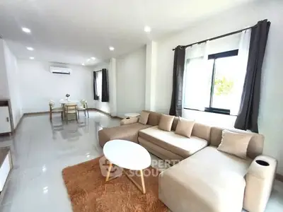 Spacious modern living room with elegant beige sofa and dining area, perfect for entertaining.
