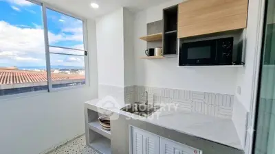 Modern kitchen with sleek design, featuring a large window and stylish cabinetry.