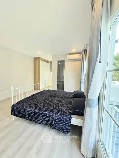 Bright and spacious bedroom with modern decor and large window view.