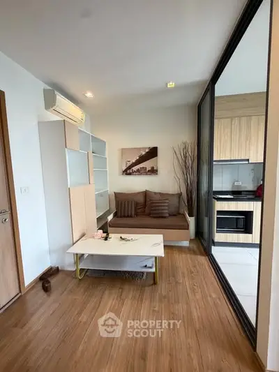 Modern living room with wooden flooring and open kitchen layout in a stylish apartment.