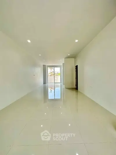 Spacious and bright living room with glossy tiled floors and large windows.