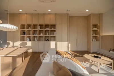 Modern living room with elegant wooden shelving and cozy seating area, bathed in natural light.