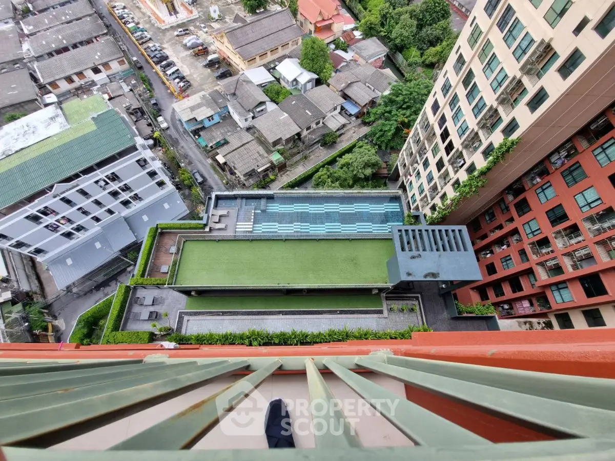Stunning aerial view of modern apartment complex with rooftop pool and lush greenery.